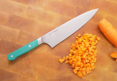the misen chef knife on a wooden cutting board with a diced carrot