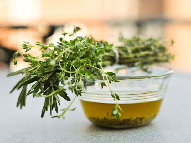 Closeup of a tied bundle of rosemary and thyme perched atop a bowl of the reserved marinade.