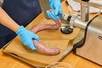 A person makes sausage using the Cuisinart Electric Meat Grinder