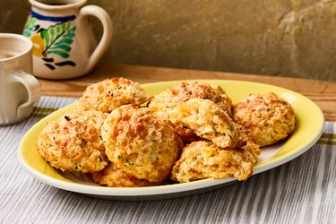 A plate of cheddar biscuits served on a striped tablecloth