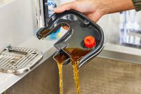 Hand pouring out coffee from Breville Bambino Plus Espresso Machine tray