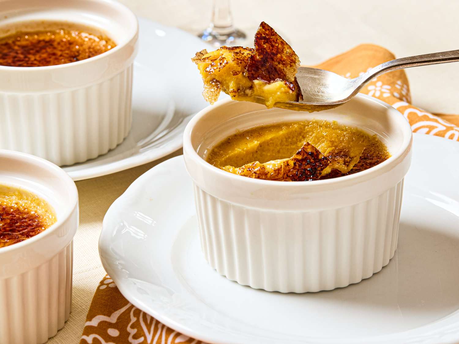 A serving of crme brle with a spoonful being removed displayed in a ramekin