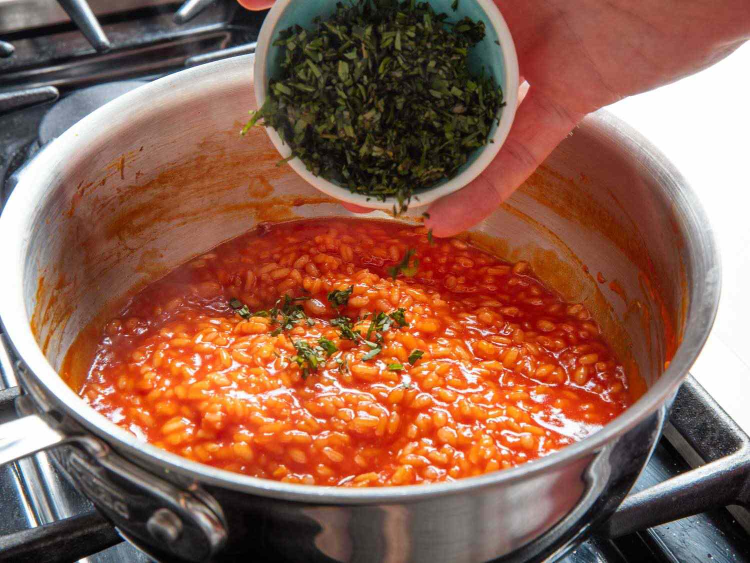 Adding chopped basil to par-cooked risotto.