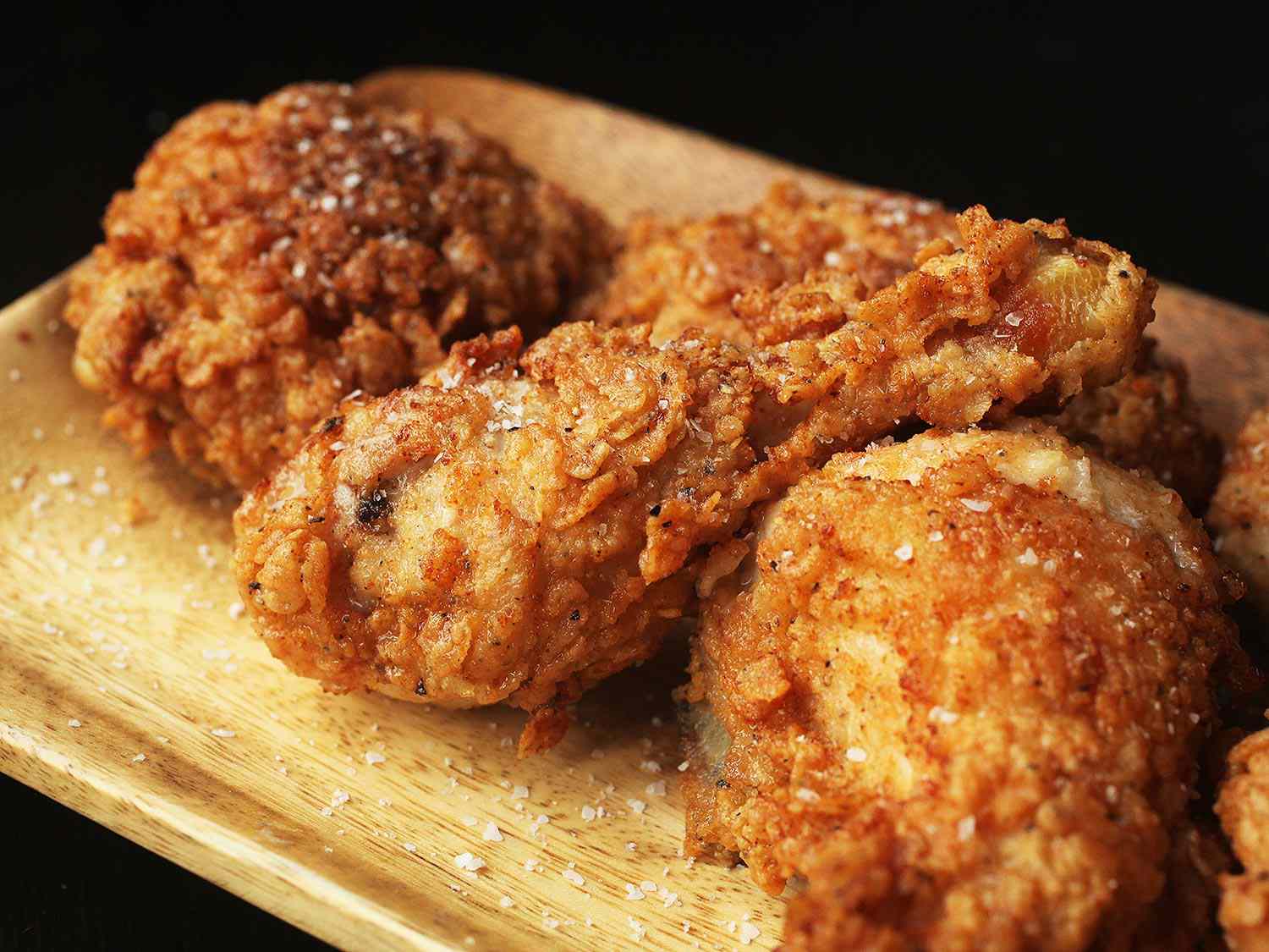 Fried chicken resting on a wooden platter.