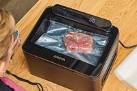 A bag of meat is vacuum sealed in the Anova Precision Chamber Vacuum Sealer