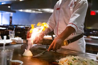 A Benihana chef making an onion volcano on the grill.