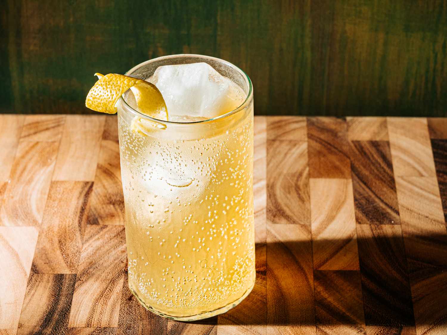 Apple crisp cocktail in a glass with a lemon peel garnish on a wooden surface