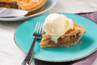 A slice of apple pie topped with a scoop of cheddar ice cream.