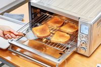 A hand using a spatula to remove toast from the Breville the Smart Oven Air Fryer
