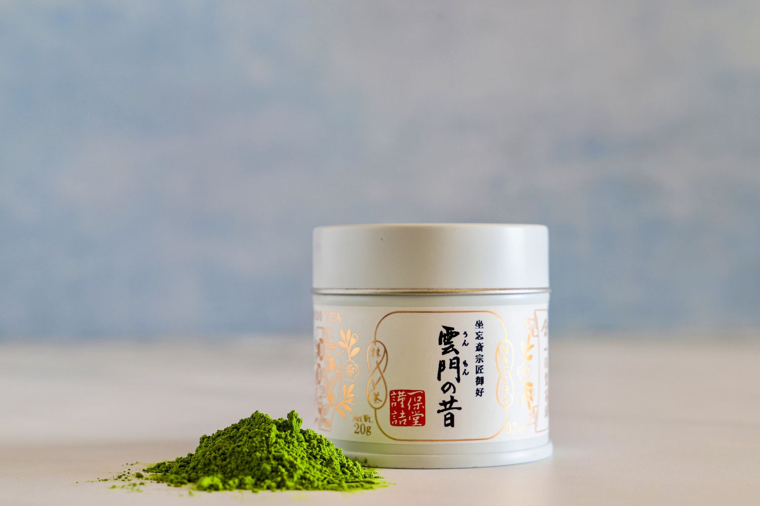 A container of Ippodo Tea Ummon Matcha next to a pile of the powder