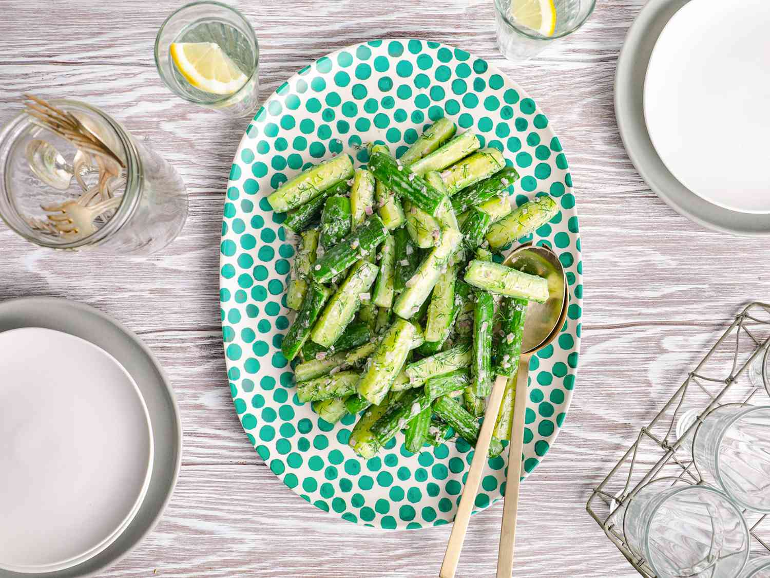 Overhead view of creamy cucumber salad, served on an oblong, polka-dotted platter.