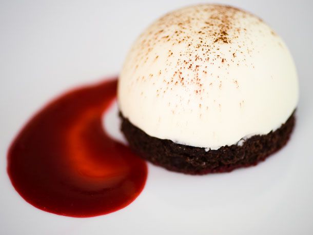 White chocolate and raspberry frozen mousse bombe plated with raspberry sauce.