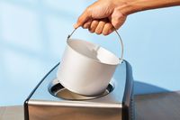 Hand removing Cuisinart ICE-100 Compressor Ice Cream and Gelato Maker bucket from its base