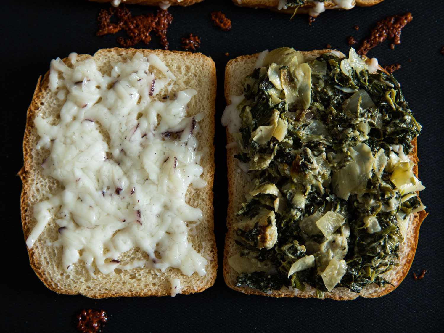 Overhead view of two cheese-topped bread slices being griddled. The slice on the left has been covered with the spinach-artichoke mixture.