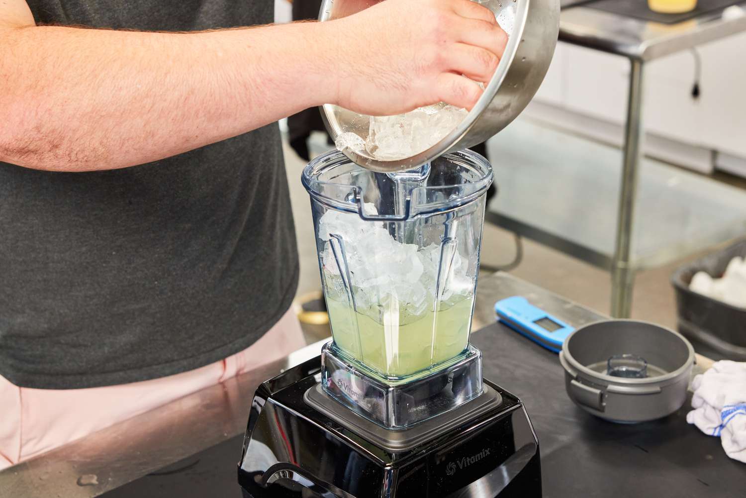 A person adding ice to a blender.