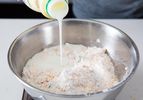 Cultured buttermilk is poured into a bowl to make the dough for cheddar bay biscuits.