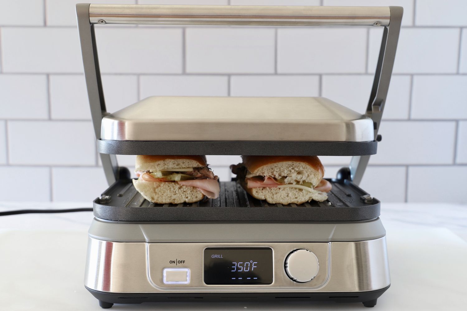 The Cuisinart griddler pressing two sandwiches.
