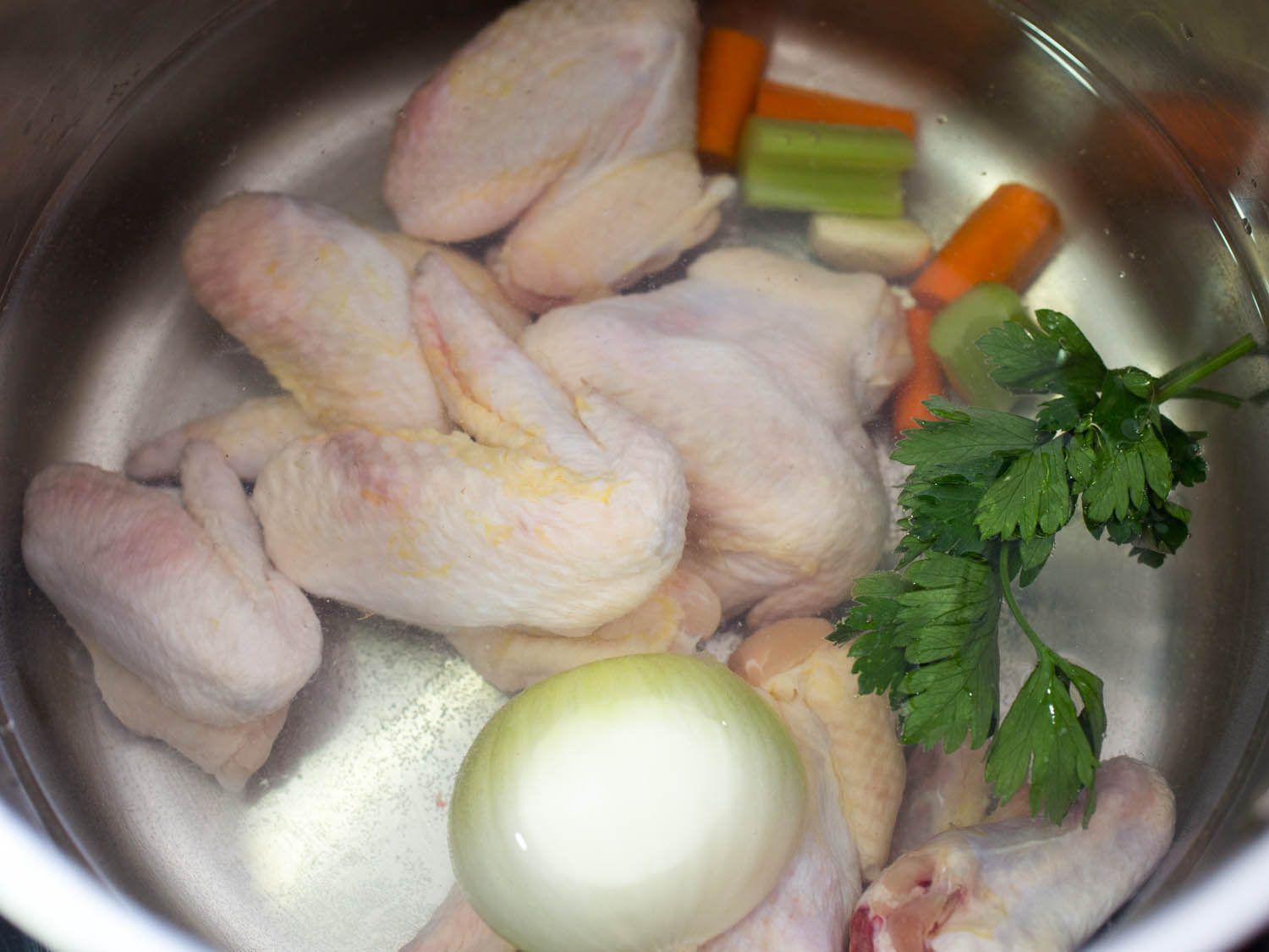 Chicken wings and vegetables in a stock pot.