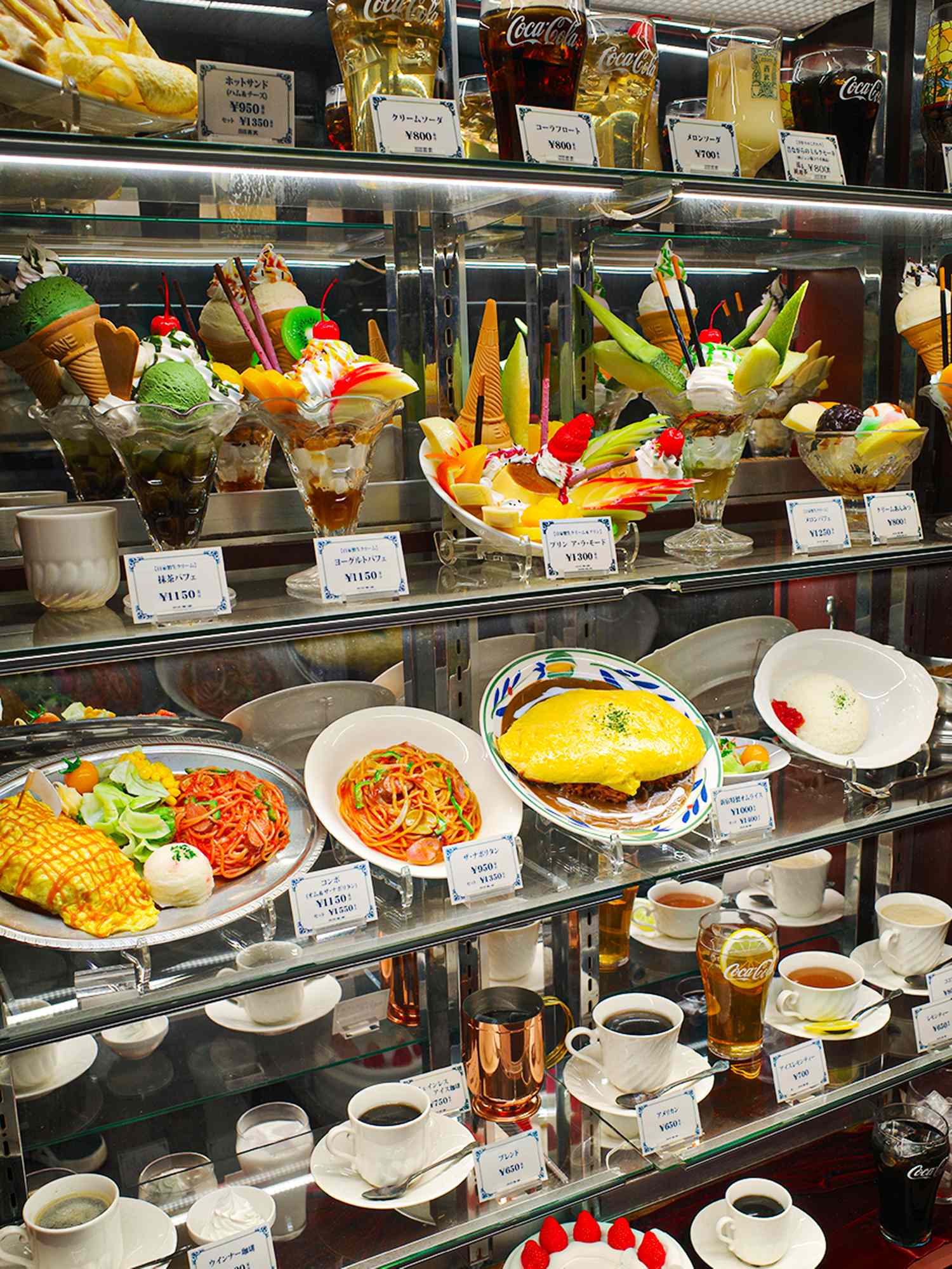 A display of foods including desserts fruit omelets and beverages on shelves in a restaurant or shop setting