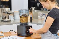 A person turning a nob on a filled Vitamix Ascent X5 Blender