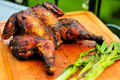 A butterflied grilled Mexican Roadside Chicken on a cutting board. 