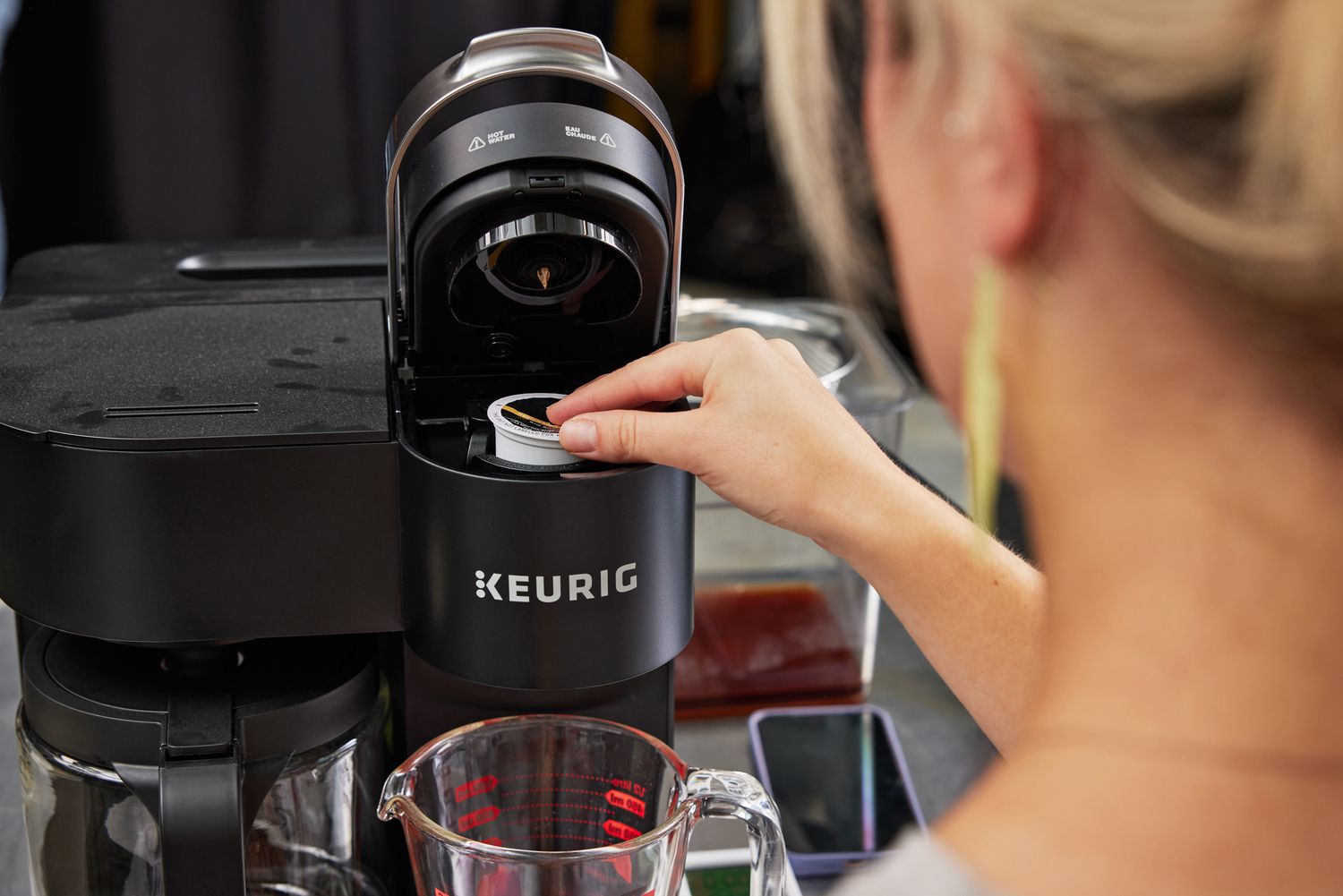 A person placing a K-cup coffee pod into a Keurig machine