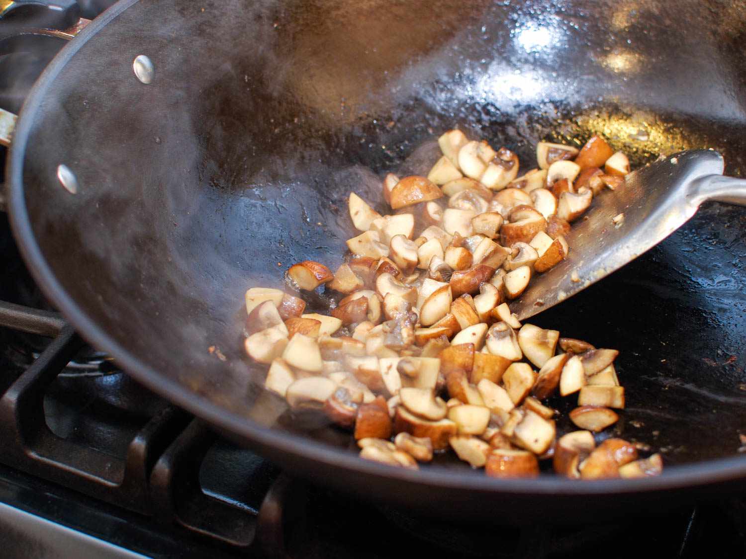 Stir-frying mushrooms in a wok for cashew chicken ding.