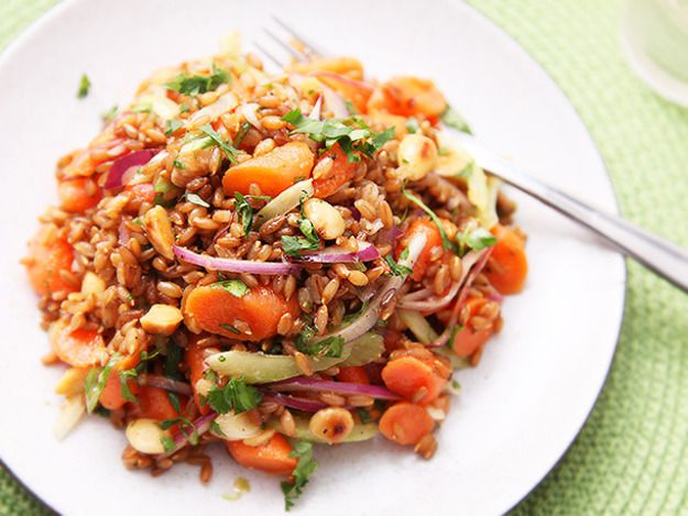 Overhead view of carrot and rye berry salad with celery, cilantro, and Marcona almonds, served on a white plate.
