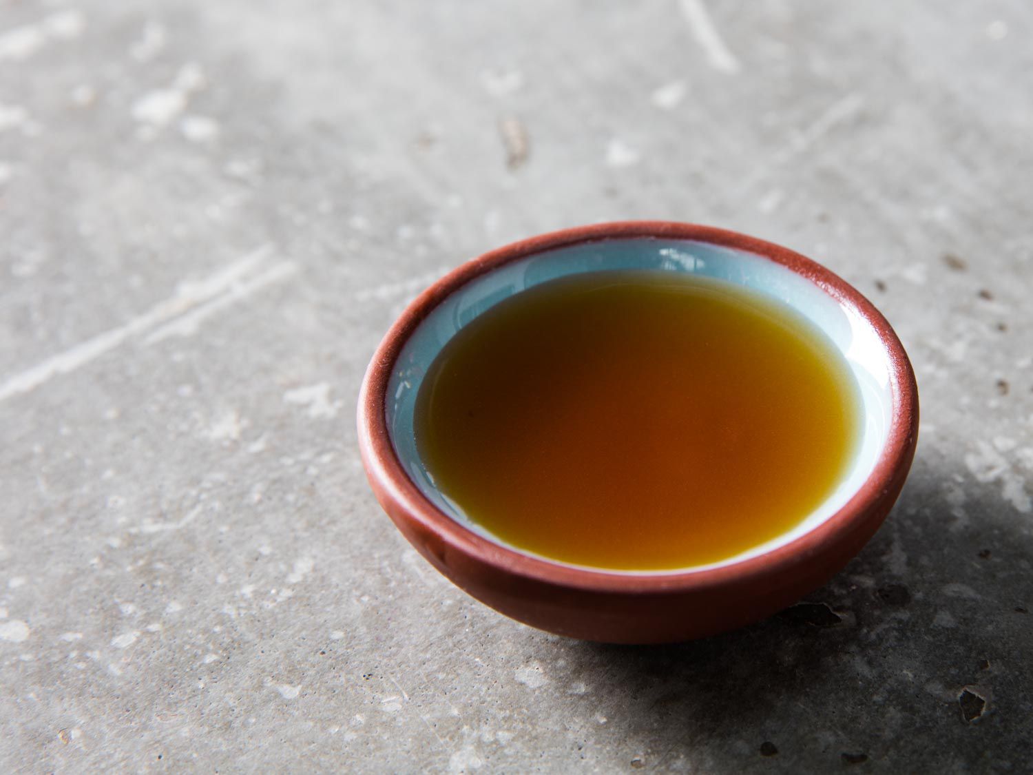 Small bowl of golden brown toasted sesame oil on grey countertop
