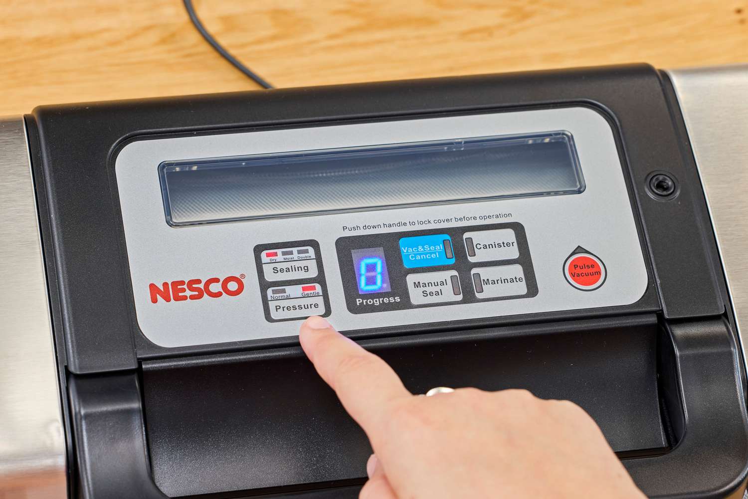 A person presses a button on the Nesco VS-12 Deluxe Vacuum Sealer