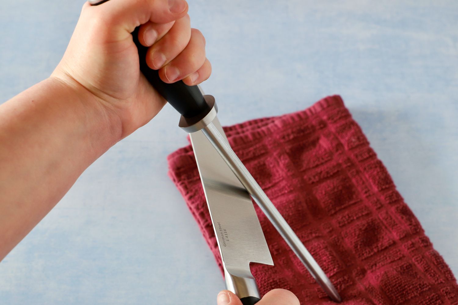 A person honing a knife using a Shun sharpening steel