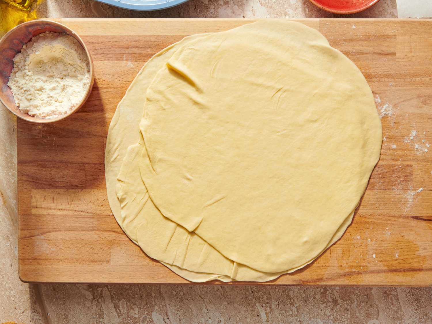 Homemade phyllo dough laid out on a wooden surface