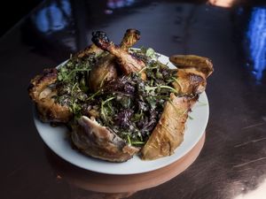 Plate of roasted chicken with greens on a dark surface