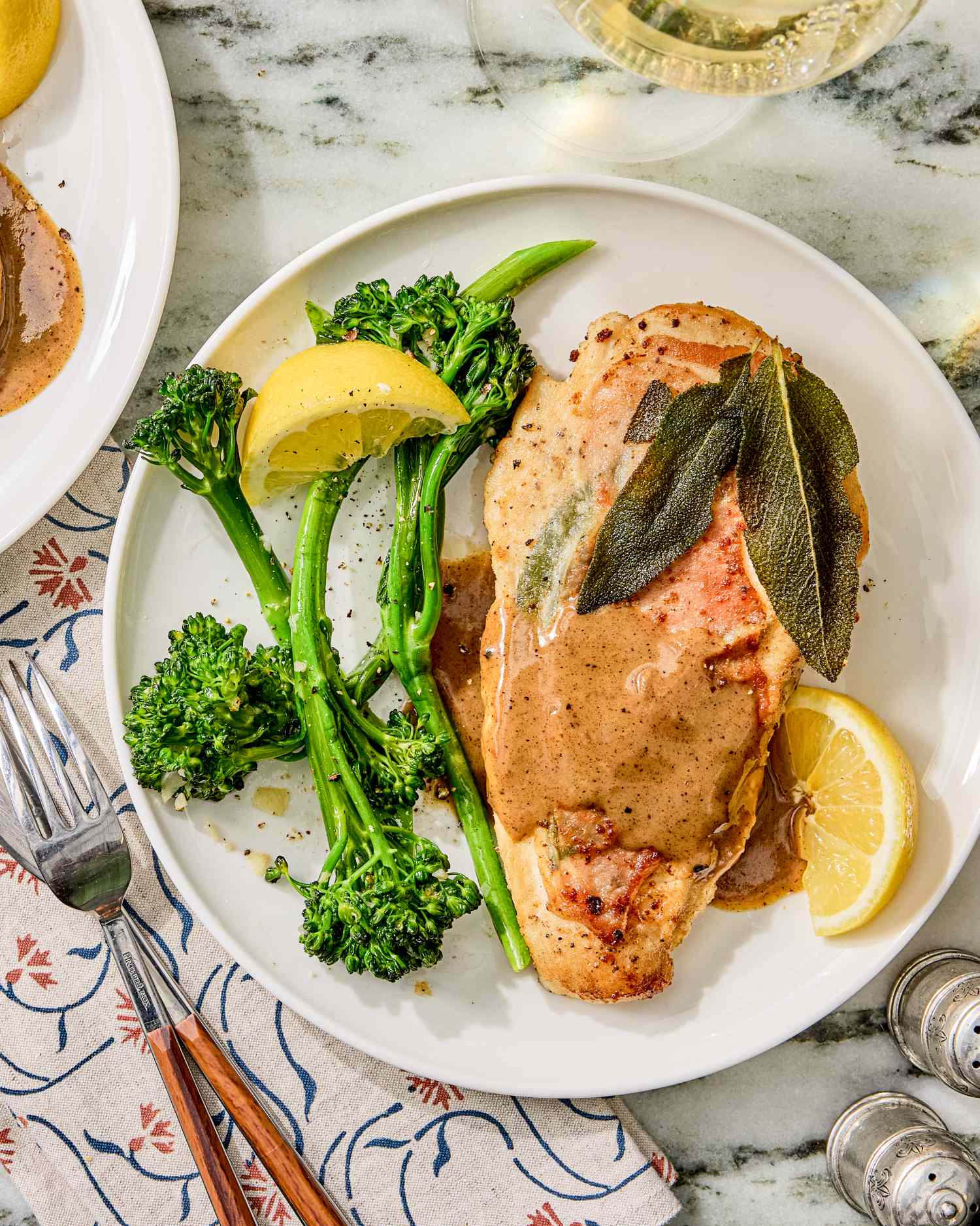 A plate of chicken saltimbocca broccolini and lemon slices