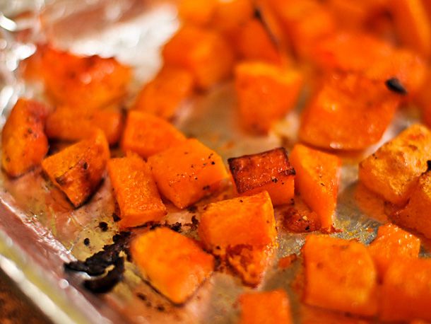 Butternut squash cubes roasting in a aluminium-foiled baking pan. 