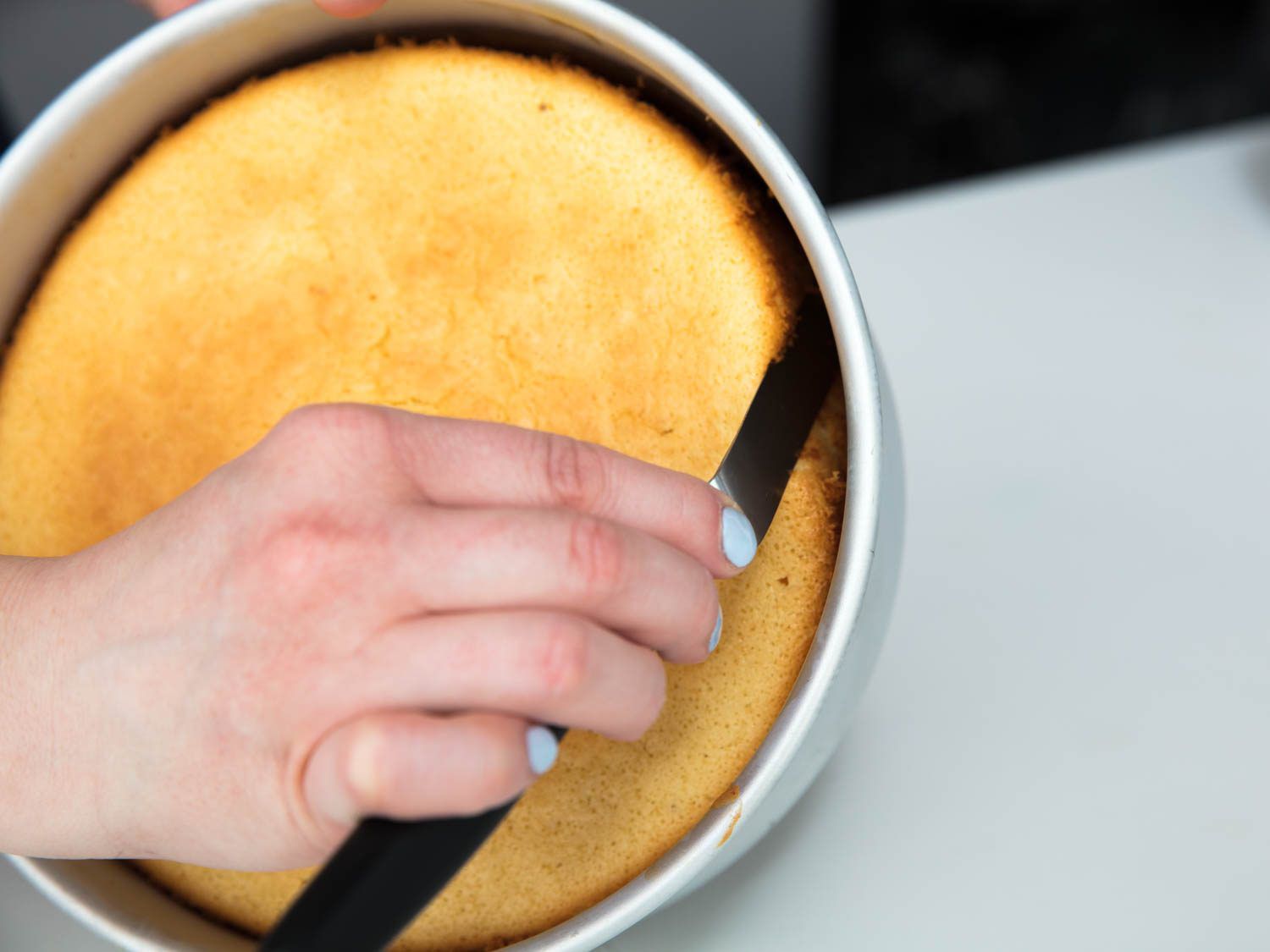 Removing chiffon cake from pan with an offset spatula. 