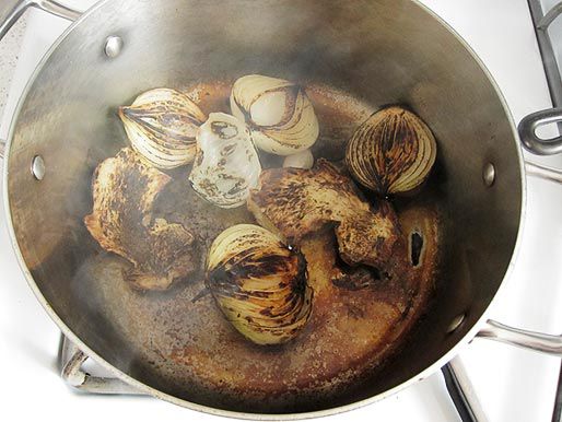 Overhead shot of onion and ginger charring in a stockpot