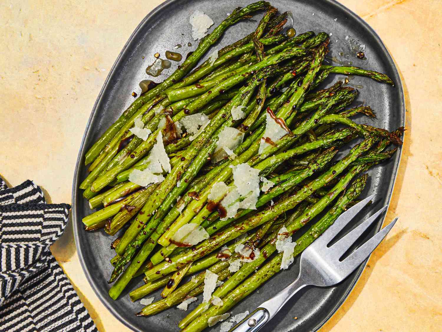 Overhead view of air-fryer asparagus, served on an oblong, slate colored platter.
