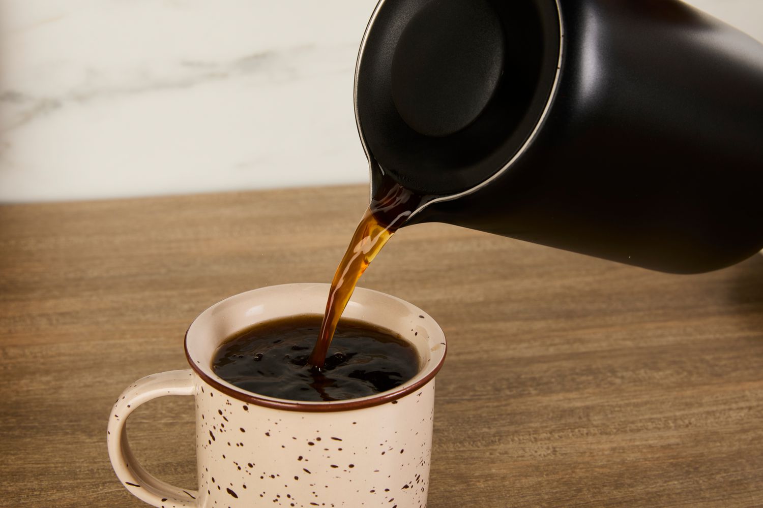 Coffee being poured from the Fellow French press into a mug.
