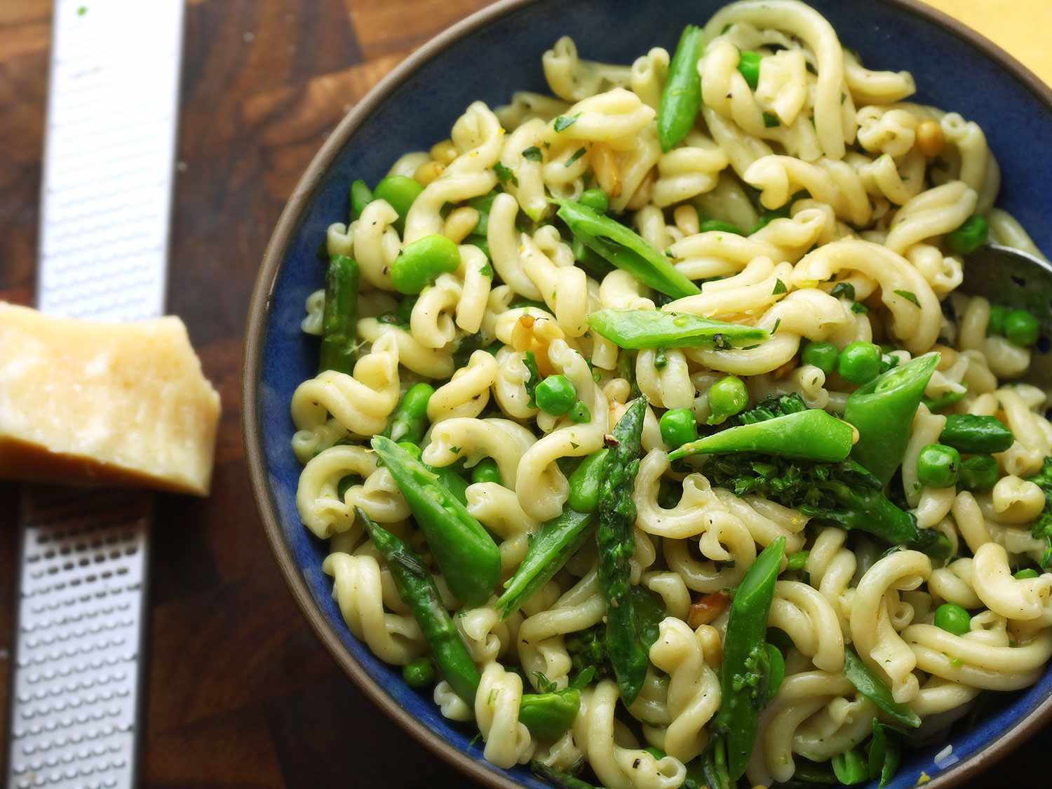 Overhead closeup of pasta primavera, served in a blue ceramic bowl.