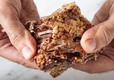 Hands pulling apart a sticky textured crispy rice treat