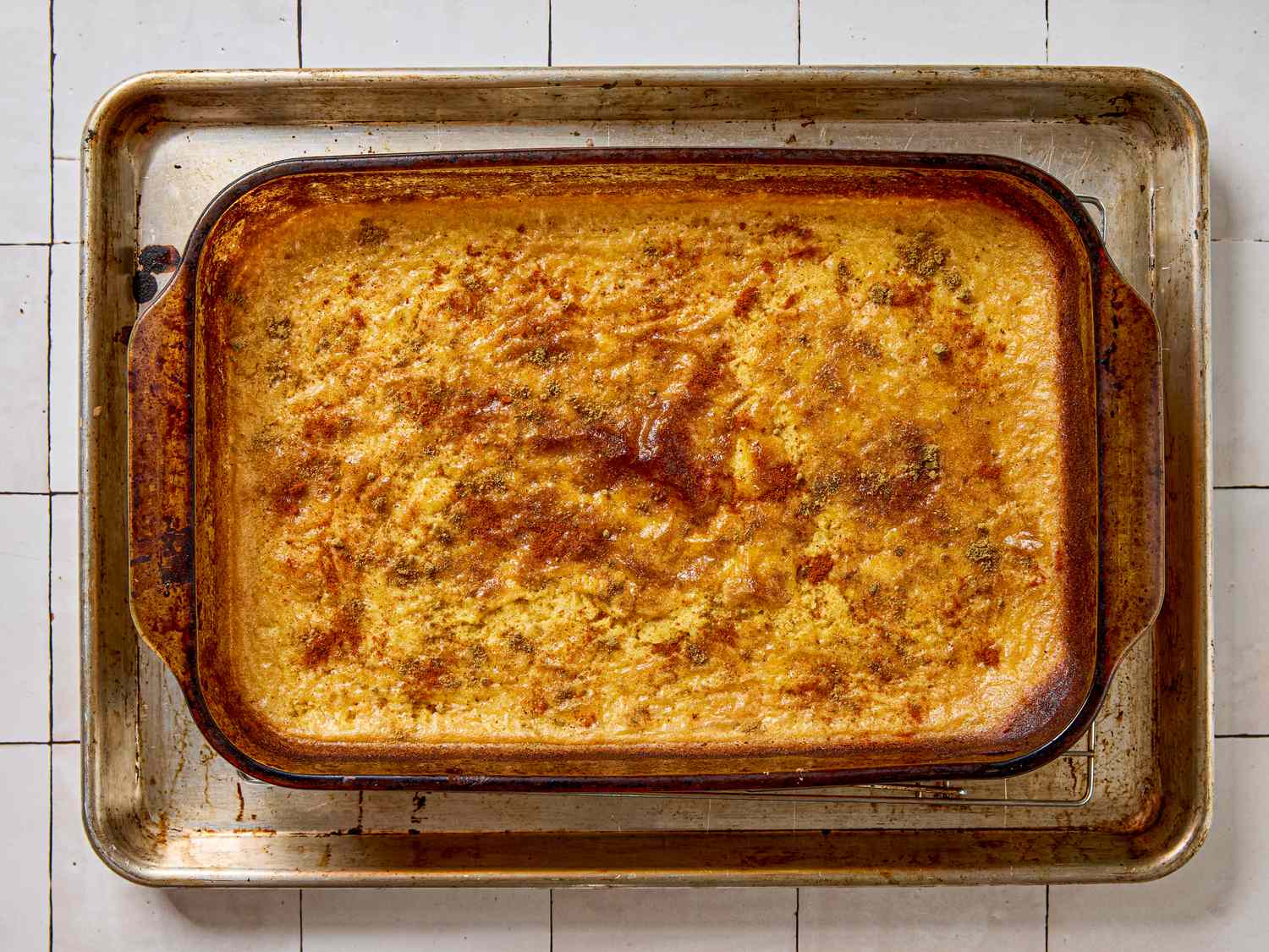 A baked casserole in a glass dish on a metal baking sheet