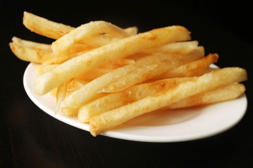 A pile of fully cooked McDonald's french fries on a white porcelain plate.