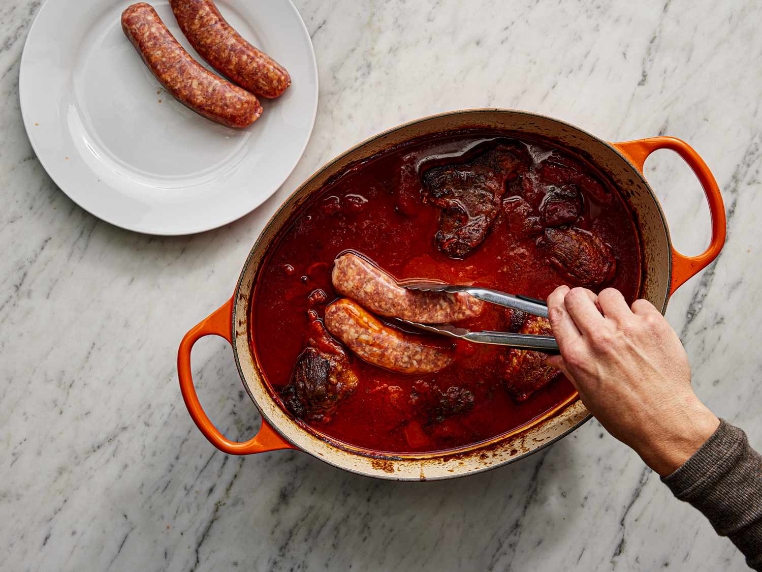 Adding sausages to the ragu sauce in Dutch Oven
