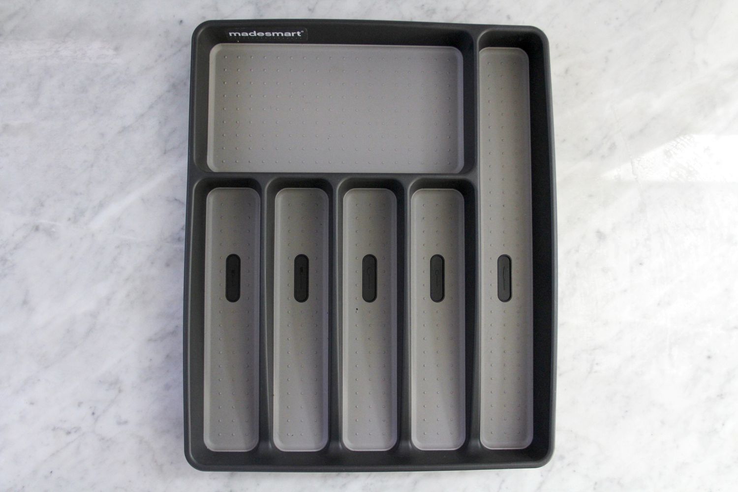 A plastic kitchen drawer organizer on a marble surface.