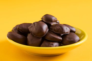 A yellow dish of homemade milk duds set on a yellow background.