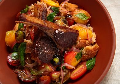 Warm panzanella salad with bread tomatoes and greens in a bowl