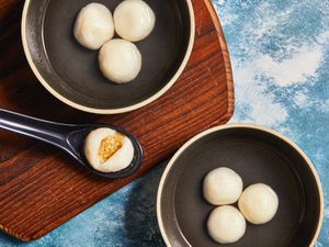 Overhead view of finished Tang Yuan on two bowls with one opened on a soup spoon