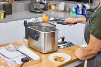 A person removing a fried item from the Breville BDF500XL Smart Fryer