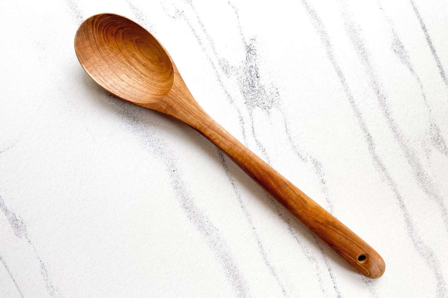 A FAAY Teak Cooking Spoon on a marblelike surface